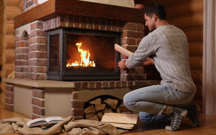 Man adding firewood in the fireplace.